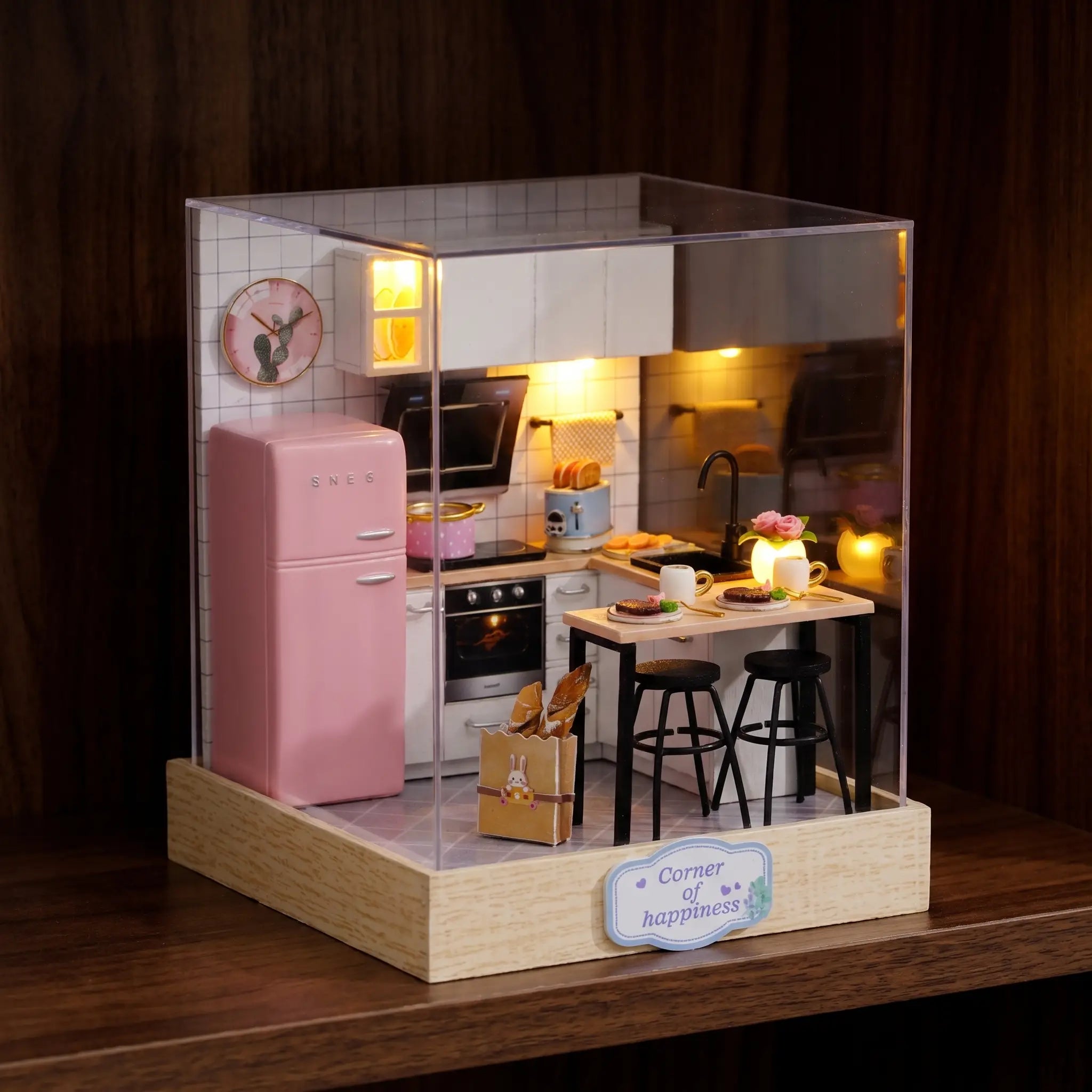 The Breakfast Bar pastel kitchen roombox glowing on a dark walnut shelf at night