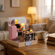 The Breakfast Bar roombox on a wooden desk at dusk beside a mug of tea