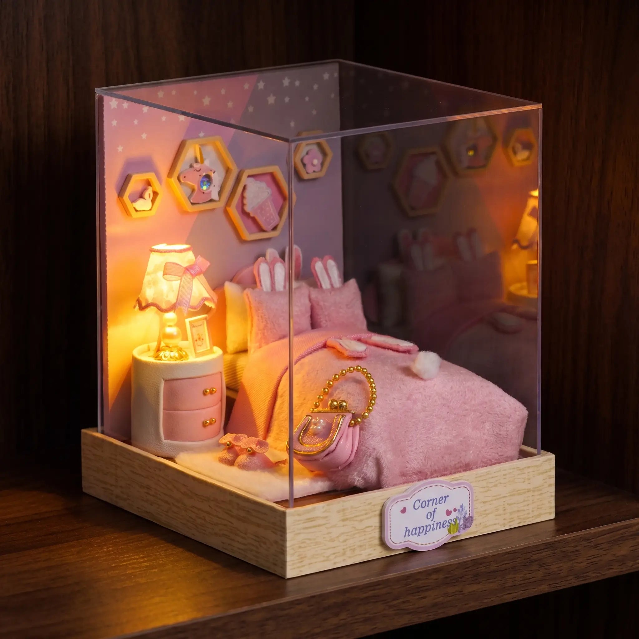 The Cottontail Room pink bedroom roombox glowing on a dark walnut shelf at night
