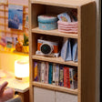 Macro detail of the bookshelf with tiny books and toy camera inside The Daydream Desk kit