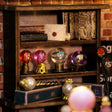 Macro detail of the jewel-toned crystal orbs on brass stands inside The Seer's Parlor kit