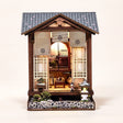 Hands assembling The Lantern House miniature kit, ending with the LED lights switching on