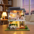 Hands assembling The Giverny Villa miniature kit, ending with the chandelier lighting up
