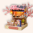 The Ramen Stall miniature kit, a glowing sakura noodle stall on a soft cream background