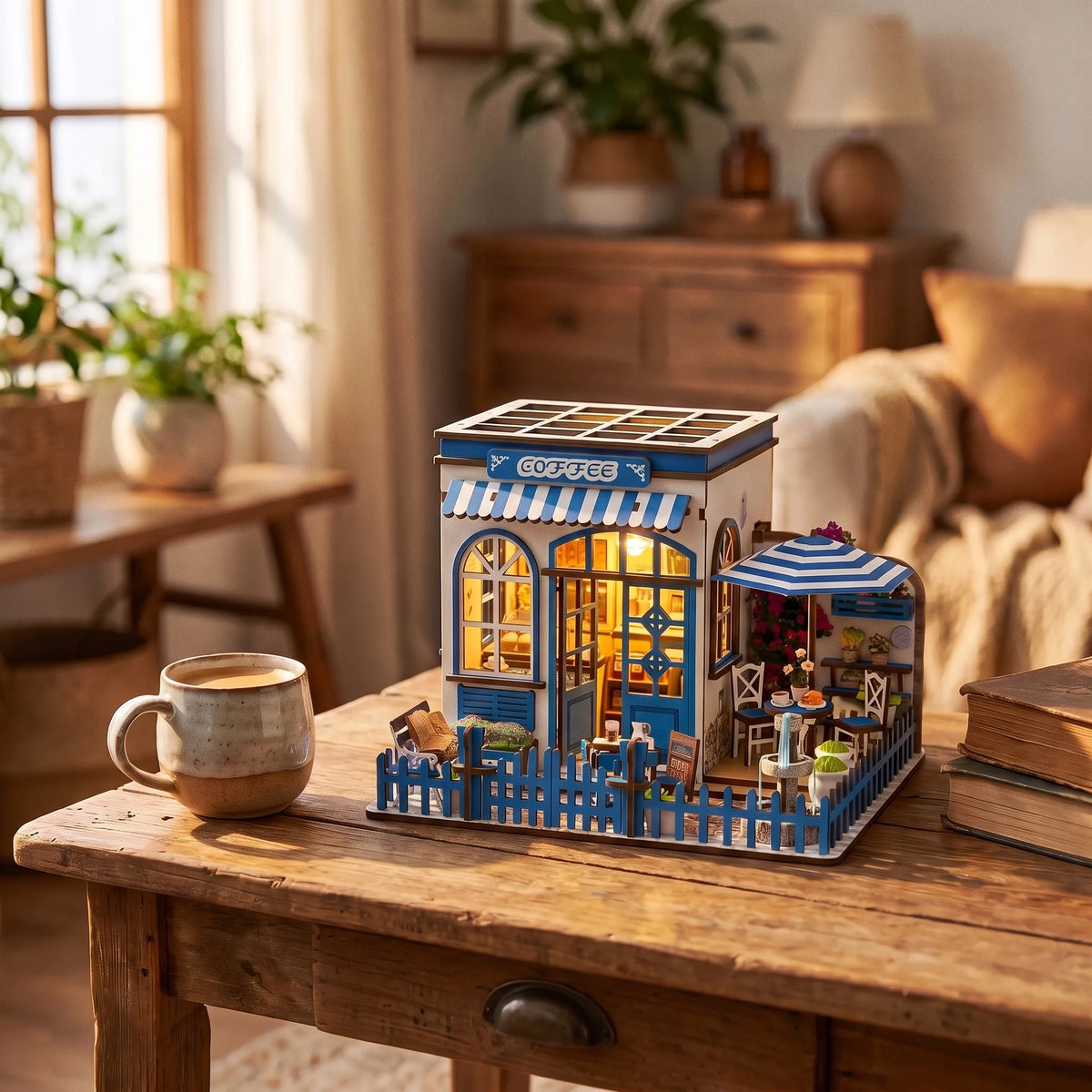 The Santorini Café miniature on a warm wood desk beside a coffee mug and books