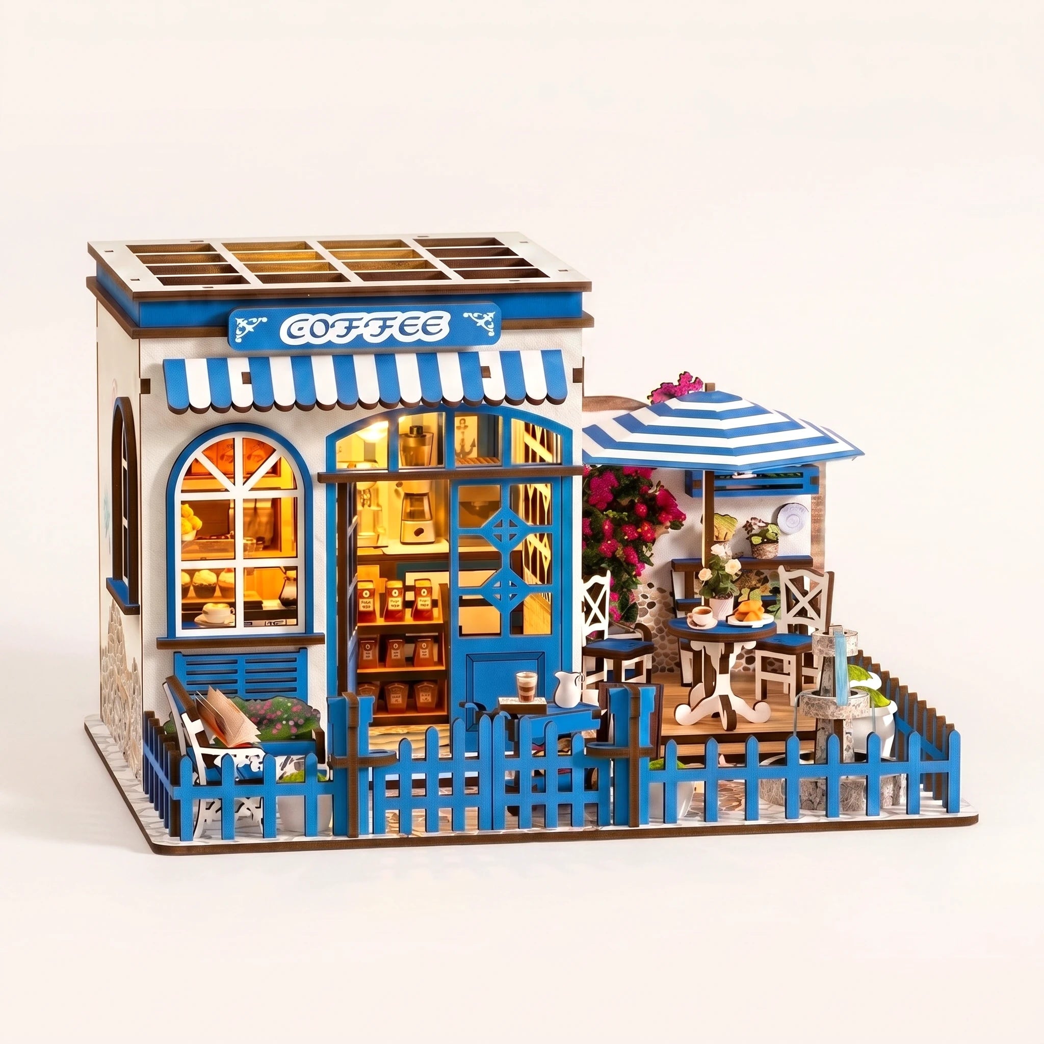 The Santorini Café miniature blue-and-white Greek coffee shop roombox on a soft cream background with warm LED lighting