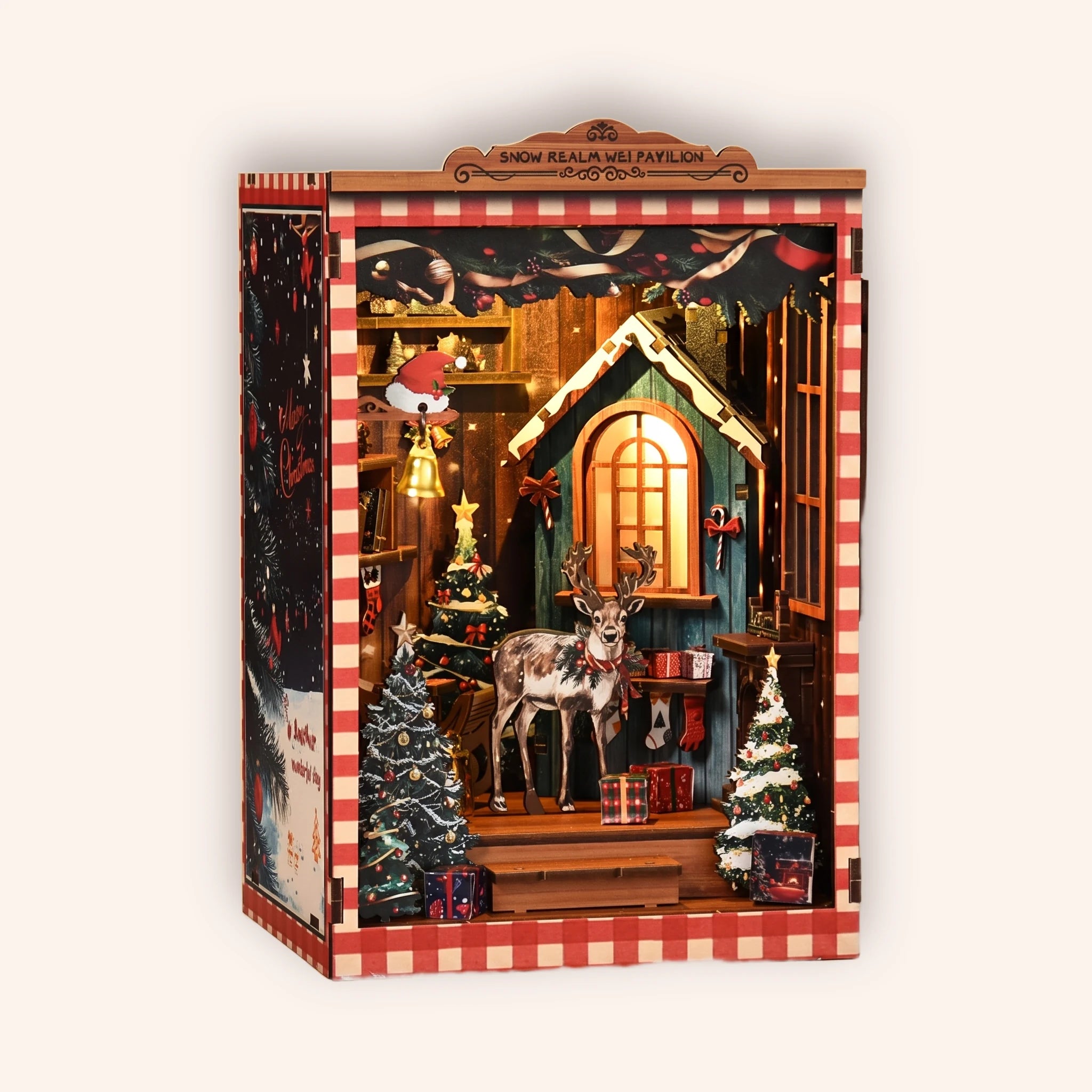The Snow Cabin DIY book nook kit, a glowing miniature Christmas log cabin with a reindeer and snowy pine trees