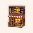The Teddy Bear Shop miniature corner shop kit on a soft cream background with warm LED lighting