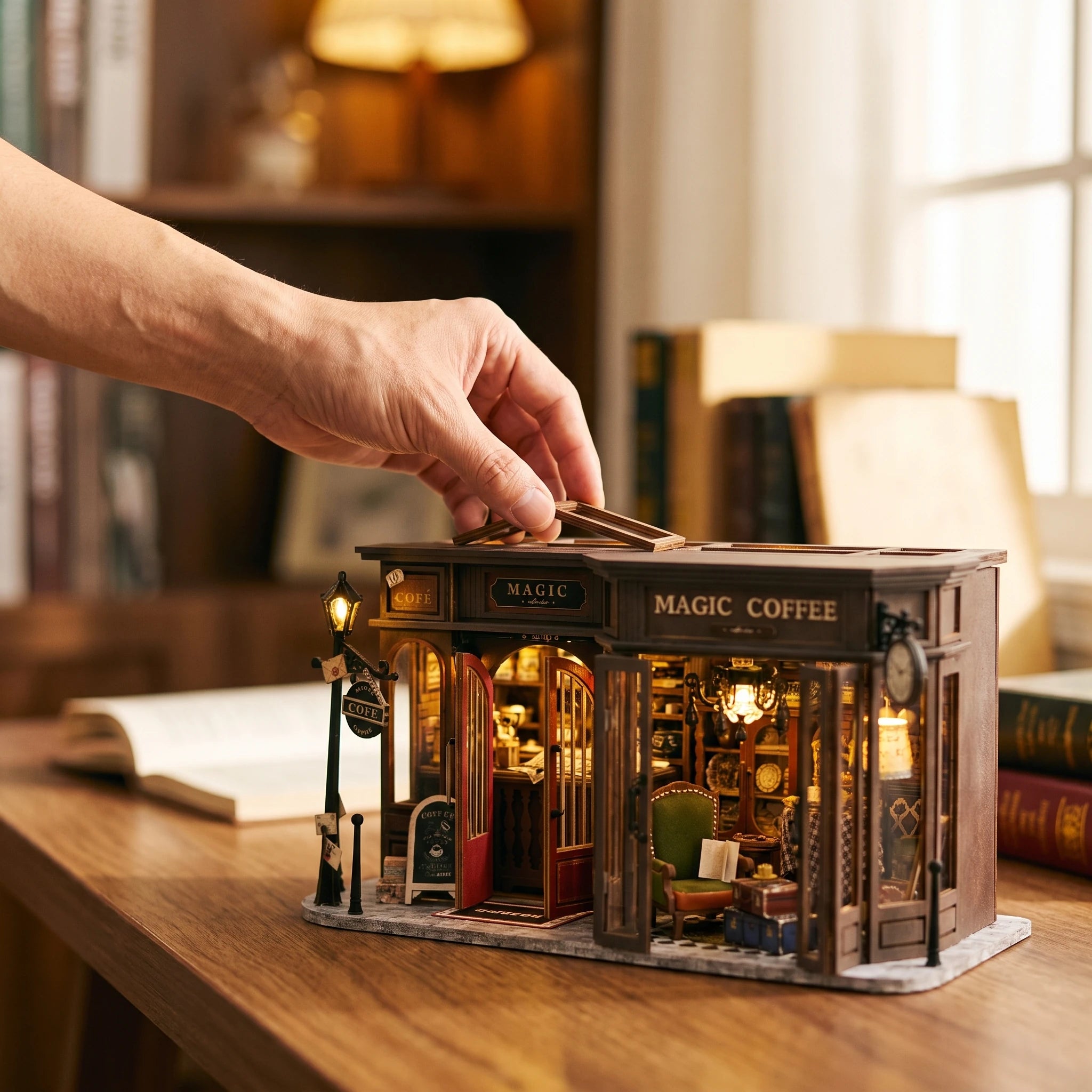 A hand placing a piece on The Alchemist's Cafe, shown in real-world scale
