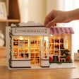 A hand placing a piece on The Berry Bakehouse, shown in real-world scale