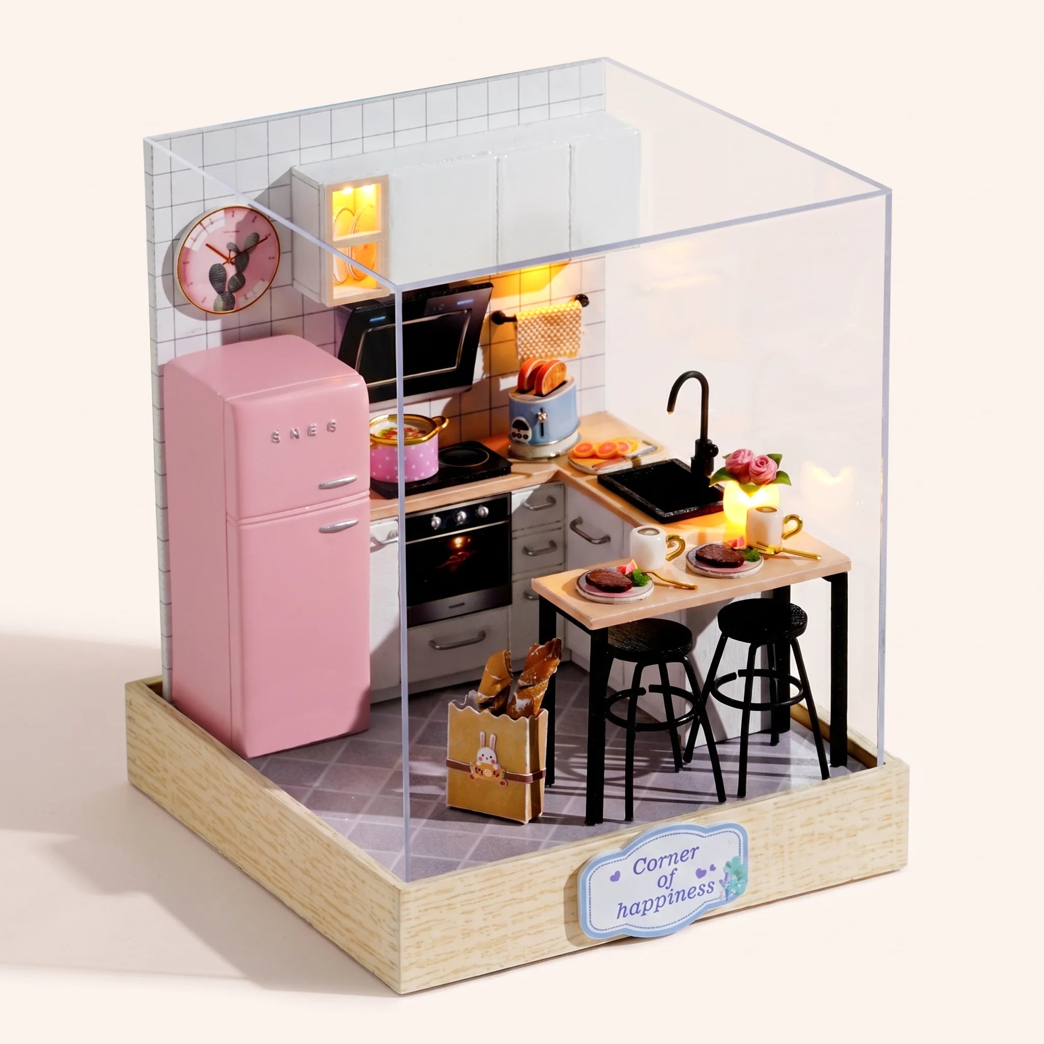 The Breakfast Bar DIY miniature kitchen kit assembled with LED lights on, on a pale blush backdrop