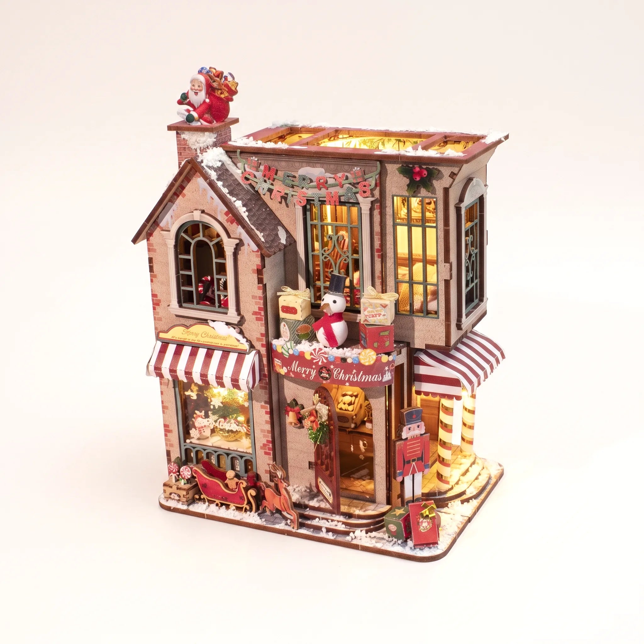 The Candy Cane Cottage DIY miniature kit with LED lights on a pale blush studio background