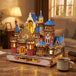 The Carousel Castle lit on a desk at dusk beside a mug of tea
