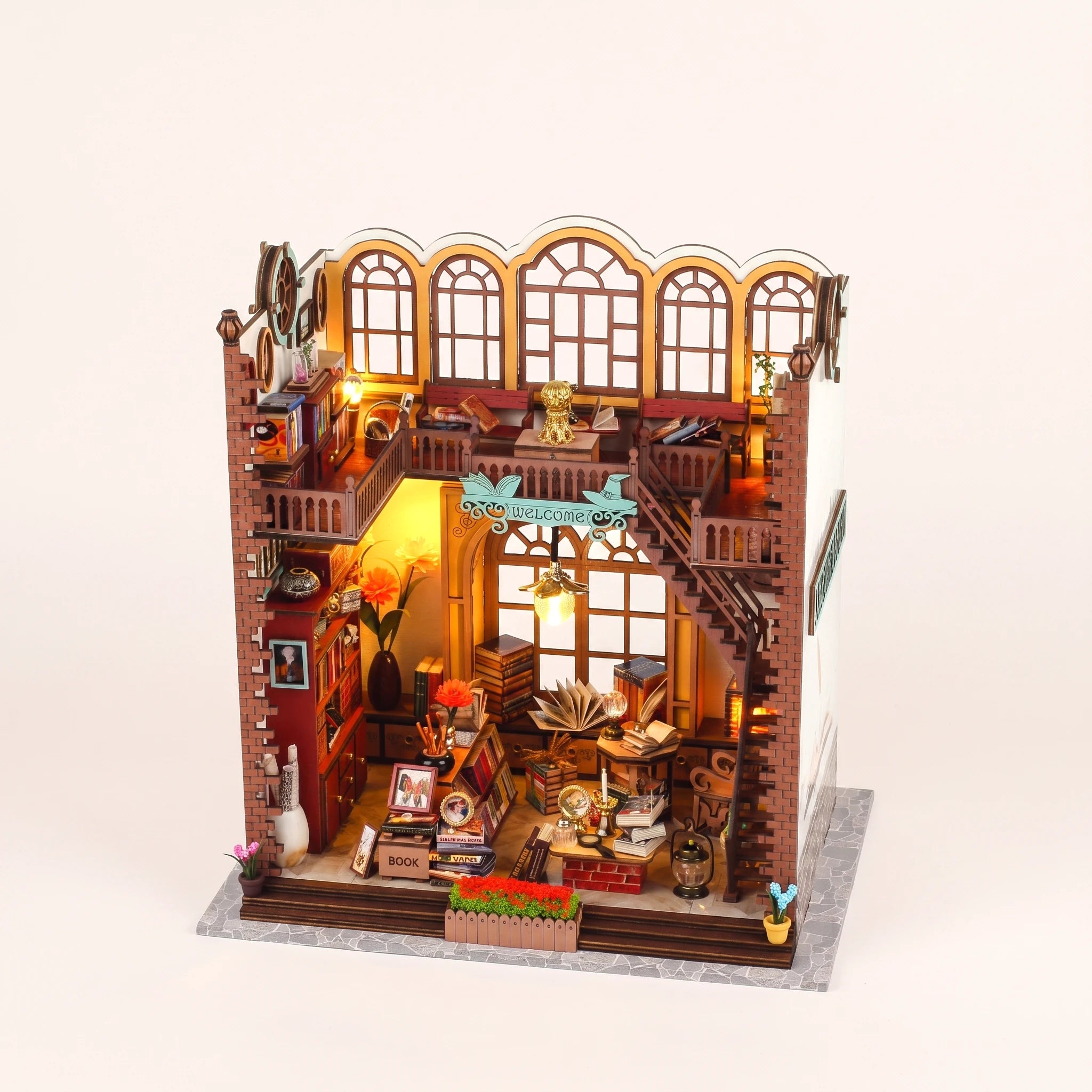 The Crystal Quill DIY miniature wizard bookshop kit with LED lights on, pale blush studio hero