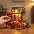 A hand placing a tiny book on The Lamplight Library, 8.3 inches tall