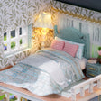 Bedroom detail: seafoam quilt, pink pillows and bedside lamp