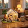 The Morning Greenhouse lit up on a desk at dusk beside a mug of tea