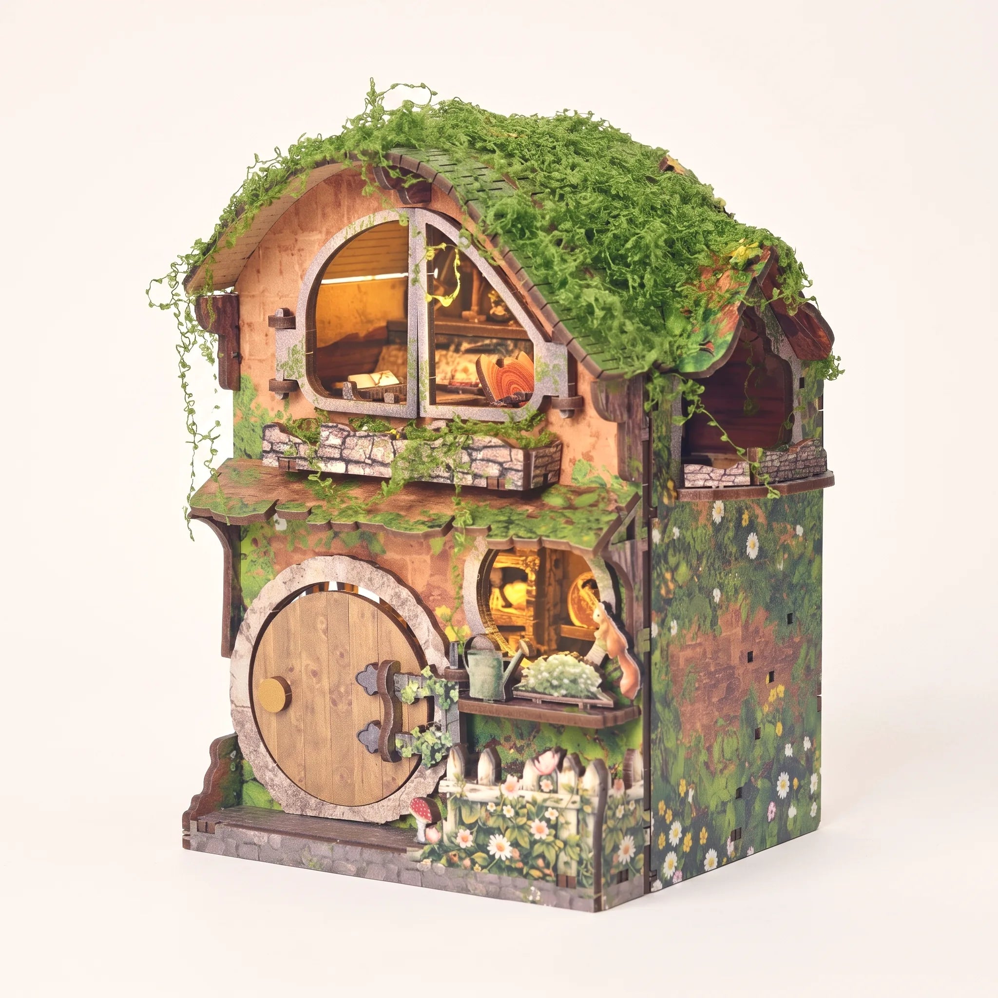 The Mossy Hollow DIY book nook kit with LED lights glowing on a pale blush studio background