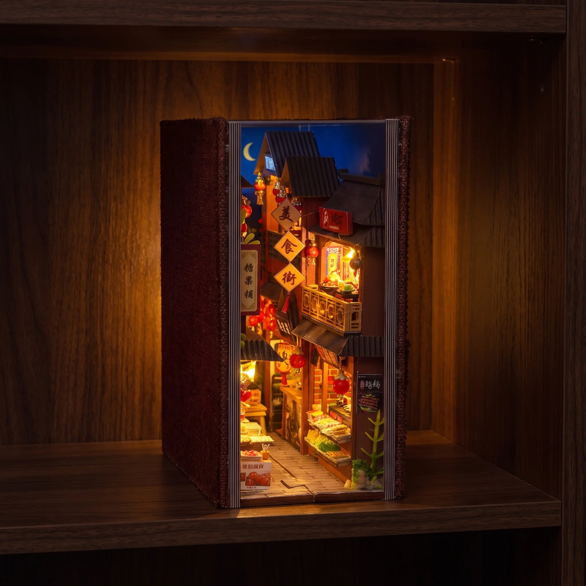 The Night Market book nook glowing on a dark walnut shelf at night