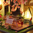 Tea table detail: pink table, tea set and bench on the wooden deck