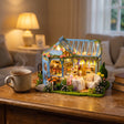The Rose Glasshouse on a desk at dusk beside a mug of tea