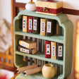 Celadon bookshelf detail with tiny classics and scroll rolls