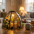 The Seedling Dome lit at dusk on a wooden desk beside a mug of tea