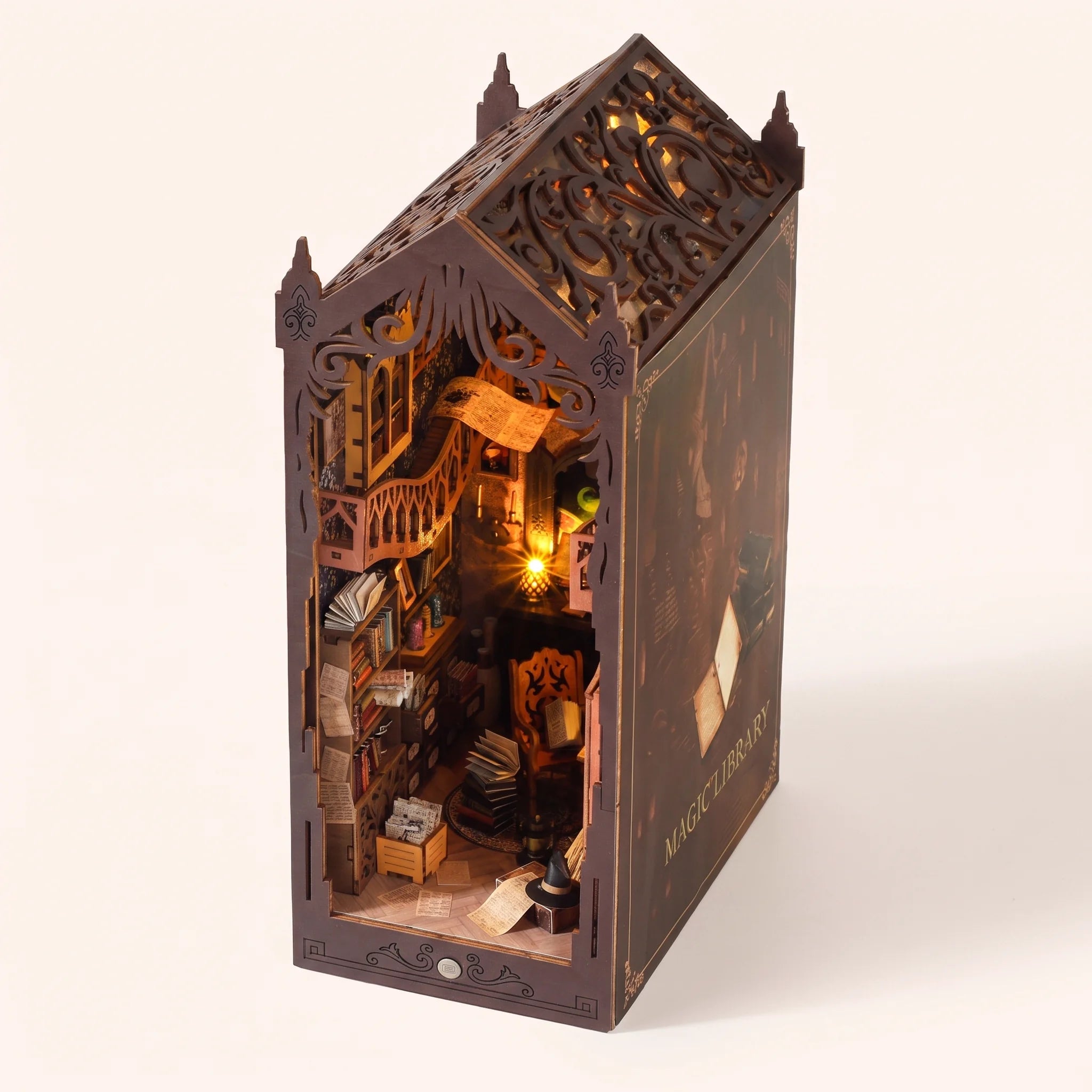 The Sorcerer's Archive DIY book nook kit assembled with LED lights on, on a pale blush backdrop