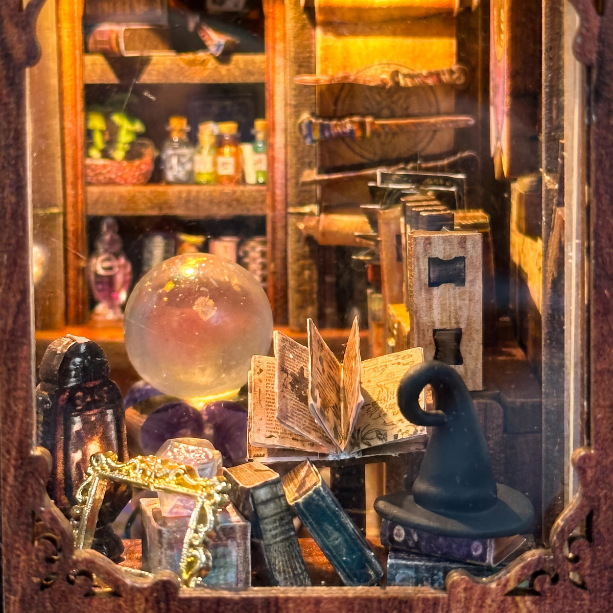 Macro of the shop window with the crystal ball, open spellbook, witch hat and potion shelves