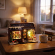 The Tinsel Emporium on a desk at dusk beside a mug of tea
