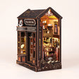 The Witch's Brew DIY book nook coffee shop kit with LED lights on, on a pale blush background