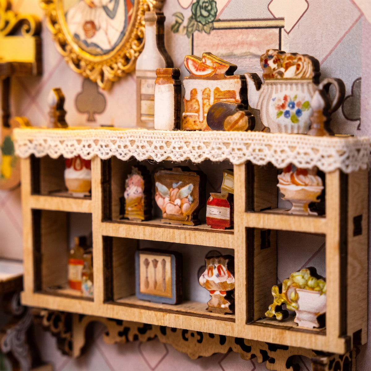Macro of the lace-trimmed dessert cabinet with tiny printed cakes inside The Wonderland Keyhole